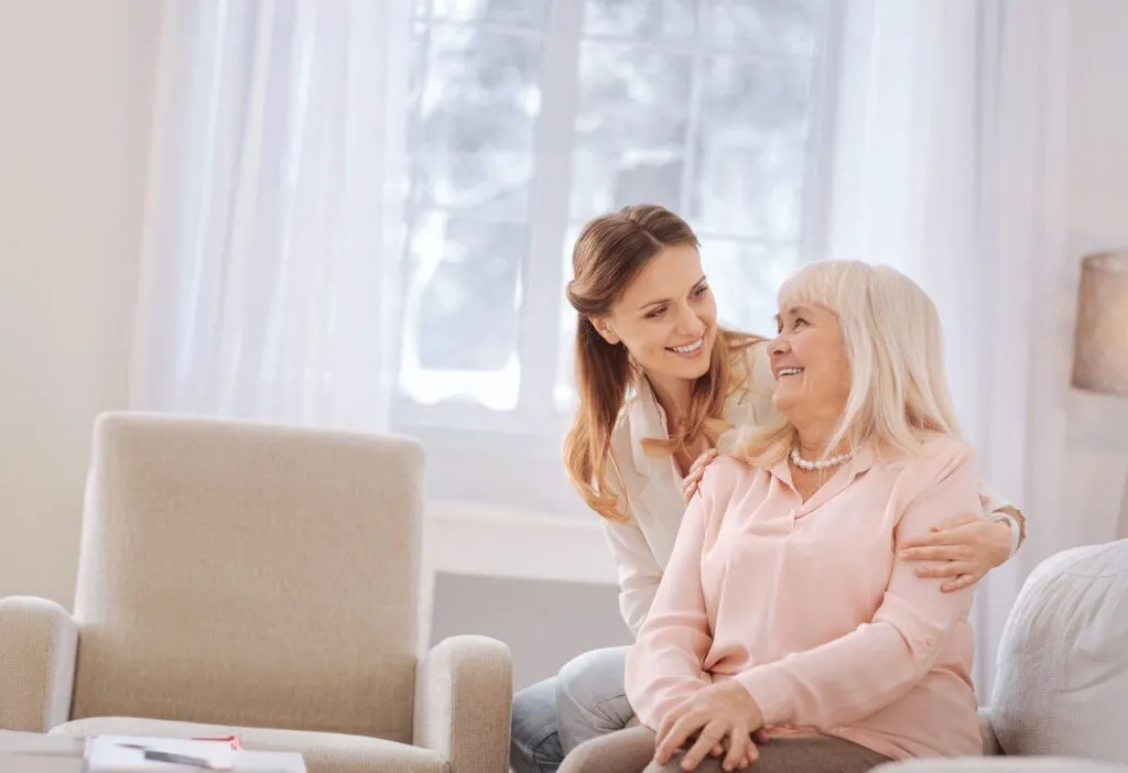Seniorin wird liebevoll von Betreuungskraft zu Hause betreut